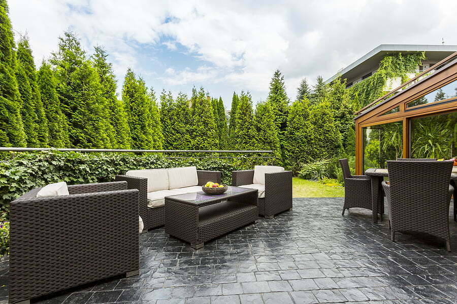 large terrace patio with rattan garden furniture set surrounded by lush greenery